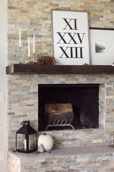 a stone fireplace with a clock above it and candles on the mantle next to it