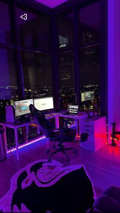 a room with two computer monitors and purple lighting