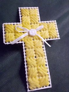 a yellow crocheted cross with a white ribbon