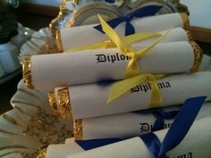 four rolled up diplomas with ribbons tied around them on a tray in front of a mirror