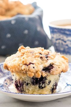 a blueberry muffin sitting on top of a plate next to a cup of coffee