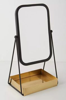 an empty mirror on a stand with a wooden box underneath it and a black metal frame