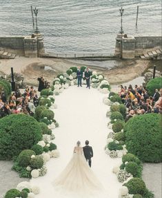 a bride and groom walking down the aisle to their wedding ceremony in front of an ocean