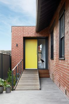 a yellow door on the side of a brick building