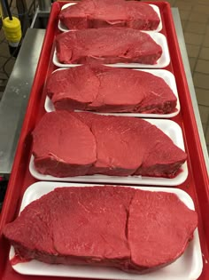 three trays filled with raw meat on top of a table