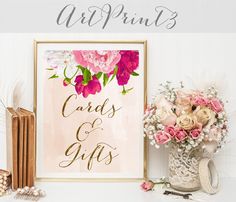 a pink and gold wedding card and gift sign with flowers in vase next to it