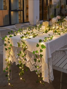 the table is set with white lace and greenery for an elegant dinner party or special occasion