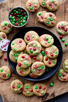 a plate filled with cookies and candy on top of a wooden table next to a bowl of m & m