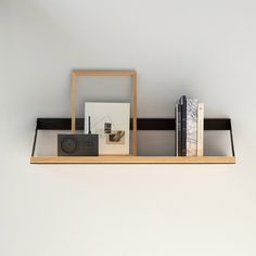 a shelf with books, pictures and a camera on it next to a white wall