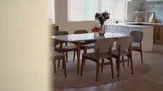 a dining room table with chairs and a vase filled with flowers on top of it