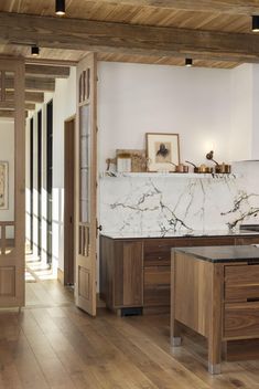 an open kitchen with marble counter tops and wooden cabinets in the center, along with hardwood flooring