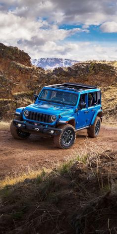 a blue jeep driving down a dirt road