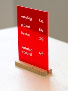 a red sign sitting on top of a white table next to a wooden block with words written in different languages