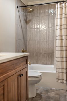 a white toilet sitting next to a bath tub in a bathroom under a shower curtain