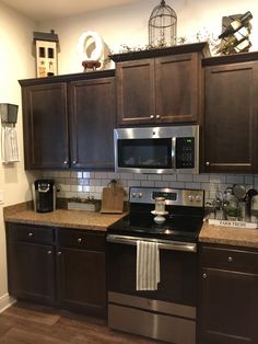 a kitchen with dark wood cabinets and stainless steel appliances, including a microwave above the stove