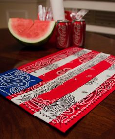 an american flag table runner with cans of soda and watermelon