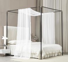 a canopy bed with white sheets and curtains