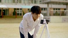 a man taking a photo with his camera on a tripod in front of a building