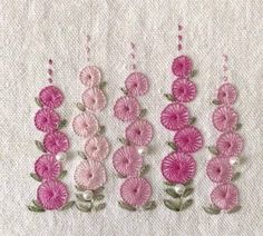 three rows of pink flowers with pearls hanging from the side on a white fabric background