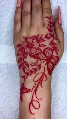 a woman's hand with red ink on it and flowers painted on the wrist