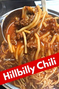 a spoon full of noodles with meat and sauce on it in a silver bowl next to a red sign that reads hillbilly chili