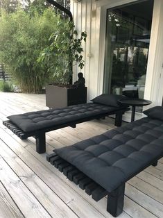 a black bench sitting on top of a wooden floor next to a planter and window