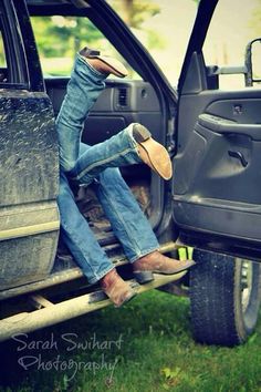 a man sitting in the back of a pick up truck with his feet on the ground