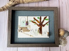 a frame with some paper cut out of the shape of a tree and ghost on it