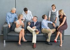 five business people sitting on a couch talking to each other in an office setting with two men and one woman