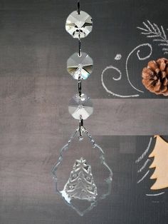 a glass ornament hanging from a hook on a chalkboard with pine cones