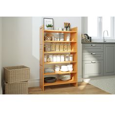 a wooden shelf filled with lots of items in a white and gray kitchen area next to a window