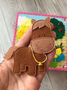 a hand holding a brown felt horse ornament