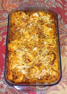 a casserole dish with cheese and meat in it on a red tablecloth