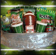 a football themed gift basket is packed with snacks, drinks and sports balls for the super bowl