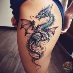 a woman's thigh with a tattoo design on it, and a dragon in the middle