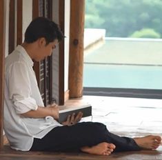 a man sitting on the floor reading a book