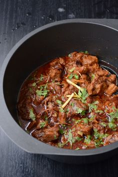 a bowl filled with meat and cilantro on top of a table