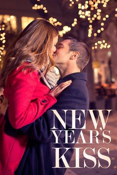 a man kissing a woman on the cheek in front of a city street with christmas lights