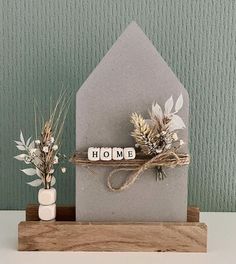 a house shaped card with the word home written on it and some flowers in vases next to it