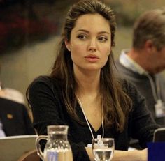 a woman sitting at a table with two laptops