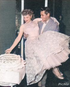 an old photo of a man and woman holding a cake