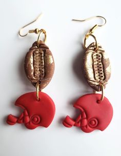 two red and gold earrings with footballs on them are hanging from earwires