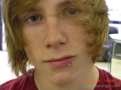 a close up of a person with frecky hair and piercing on his nose