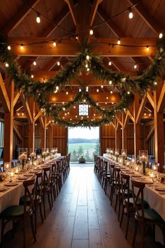 a long table set up with candles and greenery for an elegant dinner in a barn