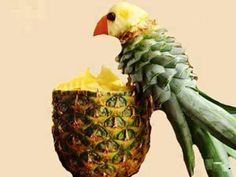 a bird sitting on top of a pineapple next to a glass filled with juice