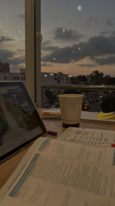 a tablet computer sitting on top of a wooden table next to a cup of coffee