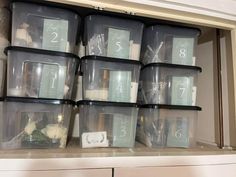 Storage bins neatly arranged by table number with the contents inside intended for use on the tables at a wedding reception. Each box contains things such as artificial flowers, flower vases, candles, table number identifier, and whatever else they may want on the table associated with that number. Pictured above is nine clear boxes, stacked three boxes high and three boxes wide.  You can see the contents inside the clear boxes and the numerical table number associated with the contents inside! Organizing Wedding Decorations, Organize Wedding Decorations, Wedding Storage Ideas, Wedding Table Organization Bins, Wedding Decor Organization, Wedding Planning Organizer, Shoe Box Storage, Wedding Setup