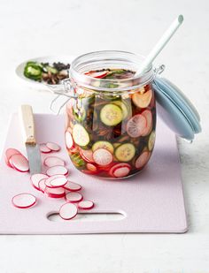 a jar filled with pickles sitting on top of a cutting board