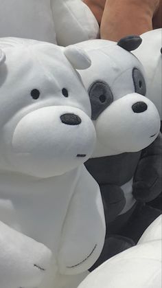 two stuffed animals sitting next to each other on white pillows with their faces close together