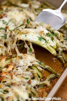 a casserole dish with green beans and cheese being scooped from the casserole